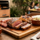 Mesa de churrasco com espetinhos, farofa e vinagrete com pessoas sorrindo ao fundo
