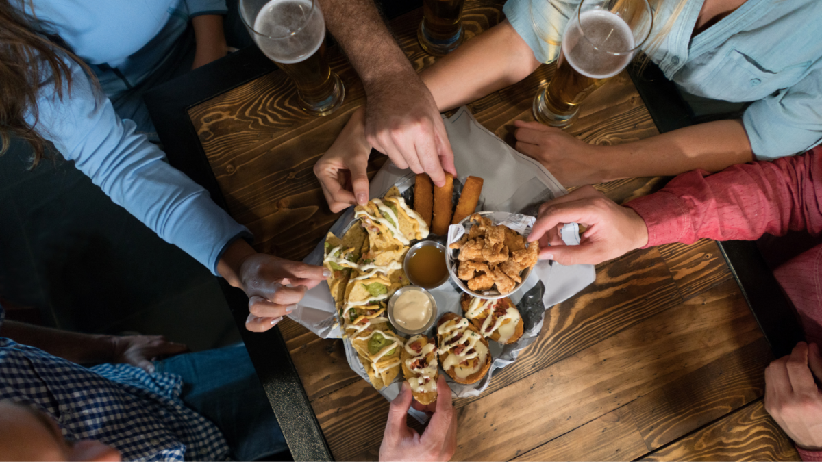 Mesa de happy hour com petiscos variados: bolinhos, dadinhos de tapioca e molhos para compartilhar