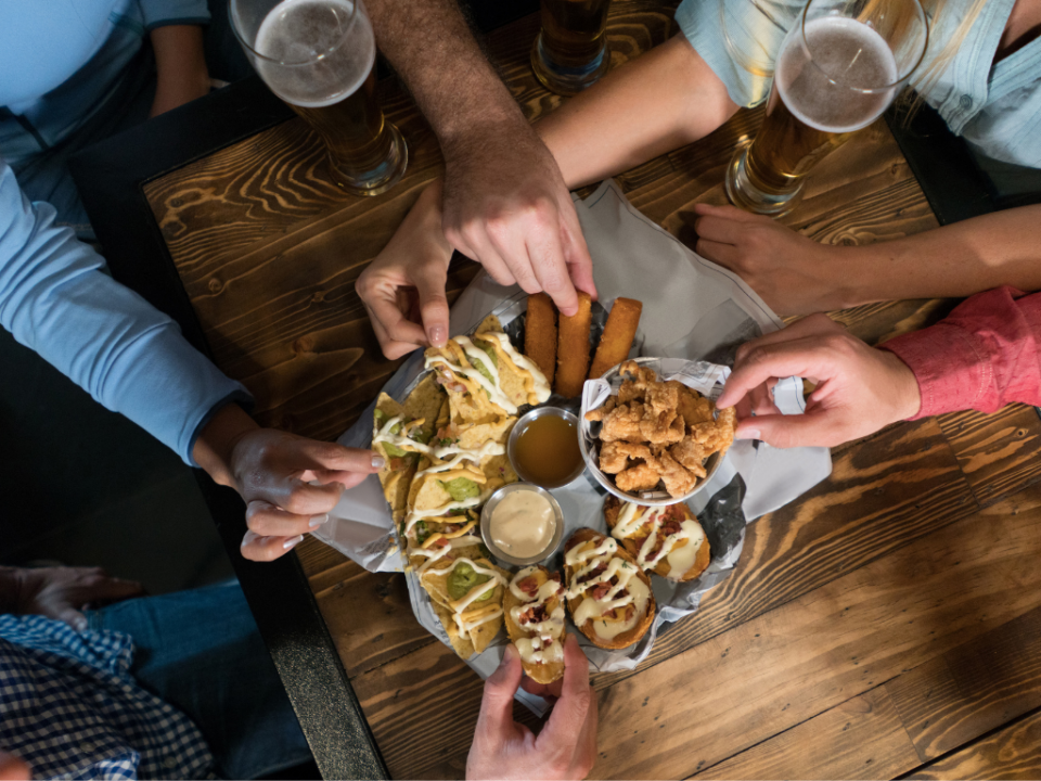 Mesa de happy hour com petiscos variados: bolinhos, dadinhos de tapioca e molhos para compartilhar