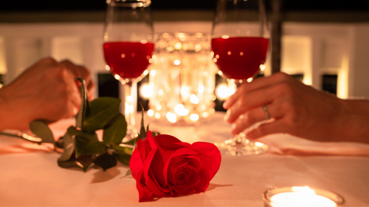 Mesa romântica posta para o jantar de Dia dos Namorados com velas, flores e pratos da culinária internacional
